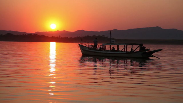 Boat with tourists on Irrawaddy river enjoying sunset, Bagan
