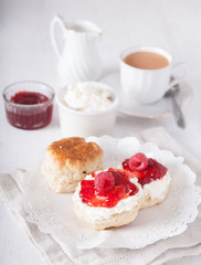 Scones with clotted cream and strawberry jam with tea on the white table