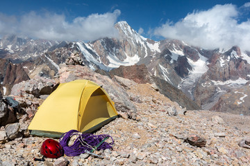 Alpine Climbers Camp in Mountains
Small Yellow Tent Climbing Gear Rope Ice Axe Red Helmet Rocky Wild Terrain Majestic Peak Range View Blue Sky Clouds