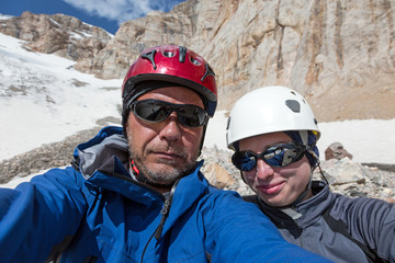 Joyful Alpine Climbers Self Portrait
Faces of Smiling Man and Woman Sport Style Clothing Protection Helmets Sunglasses High Altitude Mountain Landscape with Rock and Snow on Background