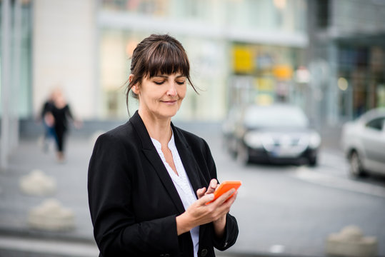 Senior business woman with phone in street