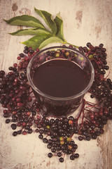 Vintage photo, Bunch of fresh elderberry with juice on old wooden background, healthy nutrition
