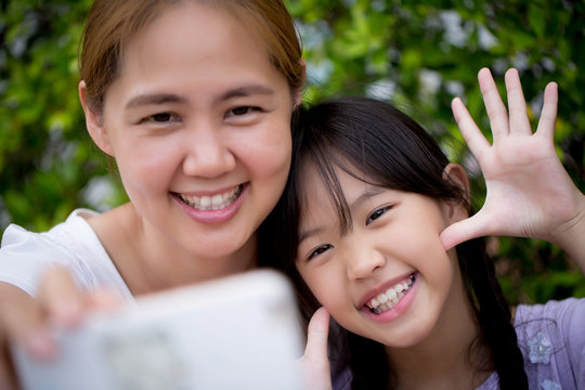 Asian mother and daughter taking selfie photograph together