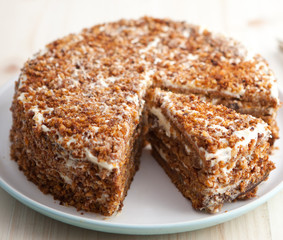 Homemade carrot and walnut cake with cut piece on a wooden table 