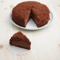 Homemade chocolate blackout cake with a cut piece on a light wooden table