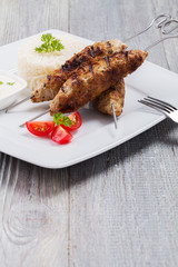 Barbecued kofta - kebeb with rice and vegetables on a plate.