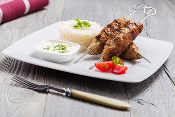 Barbecued kofta - kebeb with rice and vegetables on a plate.