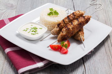 Barbecued kofta - kebeb with rice and vegetables on a plate.