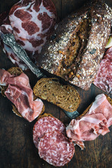 Delicious muesli bread with village ham,salami,bacon on rusty dark wooden desk