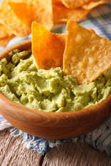guacamole and nachos chips macro in a wooden bowl. vertical