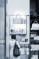 Woman considers bags in a show-window of boutique . The city of Milan is the recognized capital of the European fashion.