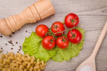 Pasta, tomatoes and pepper on a wooden background