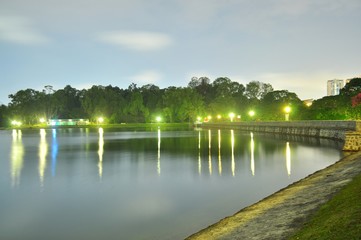 Fototapeta na wymiar Macritchie reservoir by night with trees, lamps, and light reflection on the water