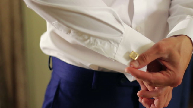 Close-up of a young happy bride wears cufflinks on their wedding
