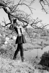Black and white picture of young pretty lady standing at tree by