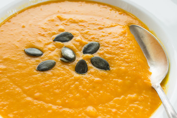 Kürbissuppe mit Kürbiskernen und Löffel