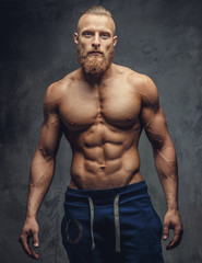 Fototapeta na wymiar Bodybuilder with beard posing over grey background.