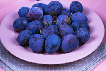 Fresh plums on pink plate
