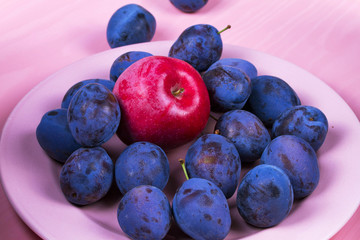 Fresh plums on pink plate