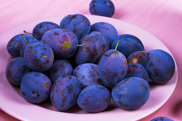 Fresh plums on pink plate