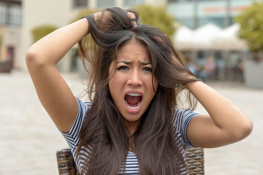 Upset frantic young woman tearing at her hair