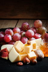 Сheese, figs, nuts and grapes on the old wooden background, sti