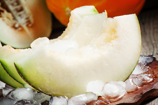 Fresh melon with ice on a wooden board, selective focus