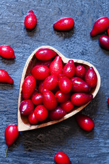 Naklejka na ściany i meble Fresh red dogwood in a wooden bowl in the shape of a heart on a