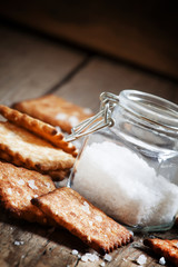 Salty cracker and sea salt in a pot on a dark wooden background,