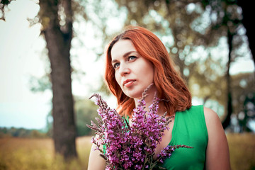 Romantic red-haired young woman in green long dress Walking
