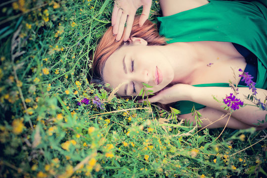 pensive dreamy attractive young red-haired woman with flowers