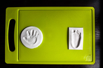 Baby handprint and footprint on green cutting board. New life concept