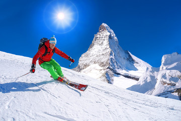 Skier skiing downhill against Matterhorn peak in Switzerland