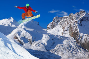 Snowboarder jumping against blue sky in Swiss Alps