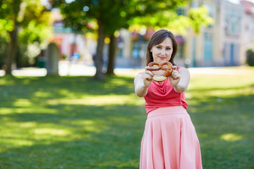 Fototapeta premium Beautiful young woman holding pretzel