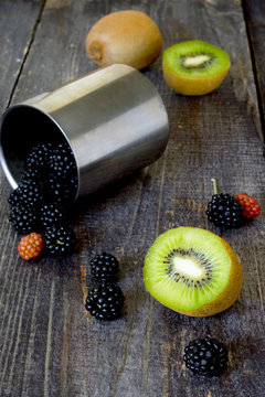 Fresh kiwi and blackberries on a wooden table, sliced kiwi fruit