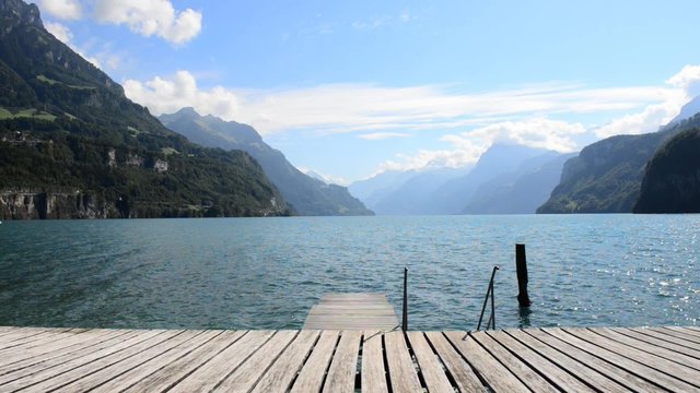 Impressive mountain landscape, lake and clouds above. In the foreground a wooden pier. Alps in Europe.
