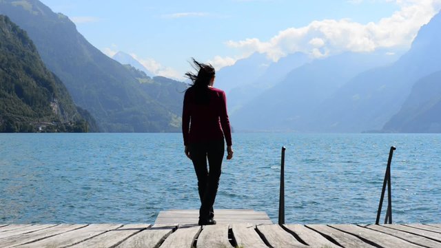 Woman sitting in lotus position and meditating on the lake. The breeze shakes her long hair.