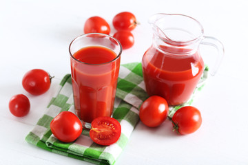 Fresh red tomatoes in basket and tomato juice in glass and jug o