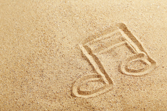 Music note drawn on a beach sand