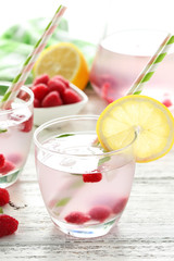 Raspberries and juice in glass on white wooden background