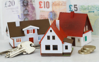 Model houses and keys with British Pounds in the background
