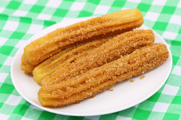 Spanish churros on plate on checkered cloth
