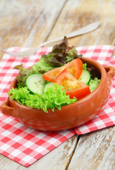 Green salad in clay bowl on checkered napkin
