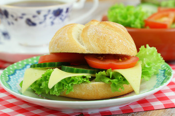 Cheese roll with lettuce, tomato and cucumber and cup of tea
