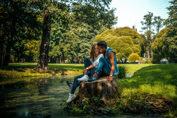 Beautiful young couple sitting near river in a park.