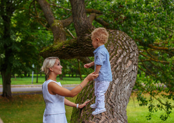 Mother playing with her child on tree in a park.