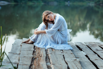 Beautiful girl sitting on the wharf bored.