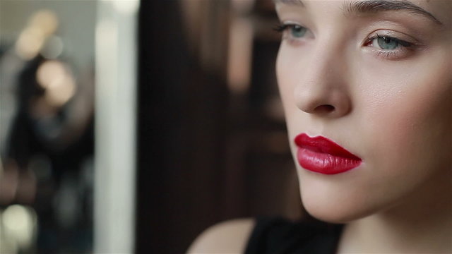 Red lipstick on lips of seductive young model. Professional make-up: finishing contour detail. Close-up