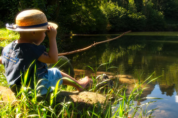 child plays to be a fisherman near the lake